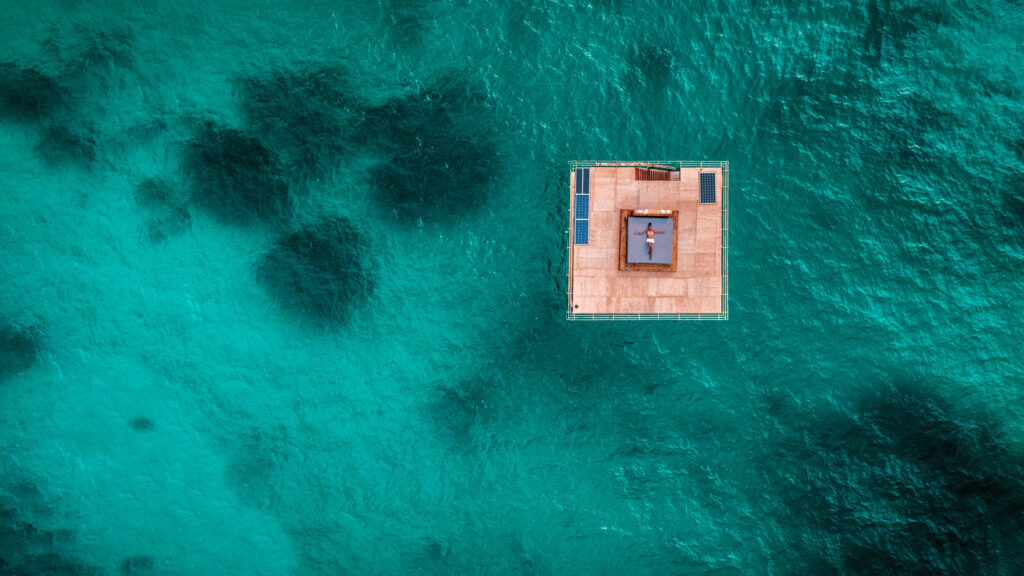 Image of the floating underwater room at Manta Resort on Pemba Island, Tanzania from overhead. Guest can be seen relaxing on a top-level sun tanning bed | Planet Africa Safaris | Blog | Kwanini: The Manta Resort